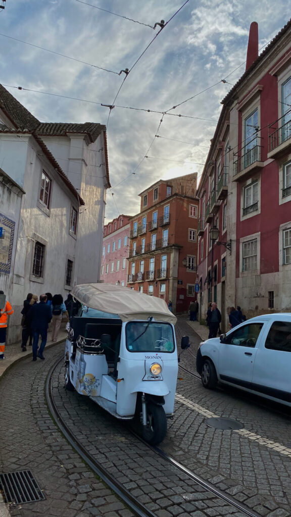 view of a alfama street with lisbon tuk tuk